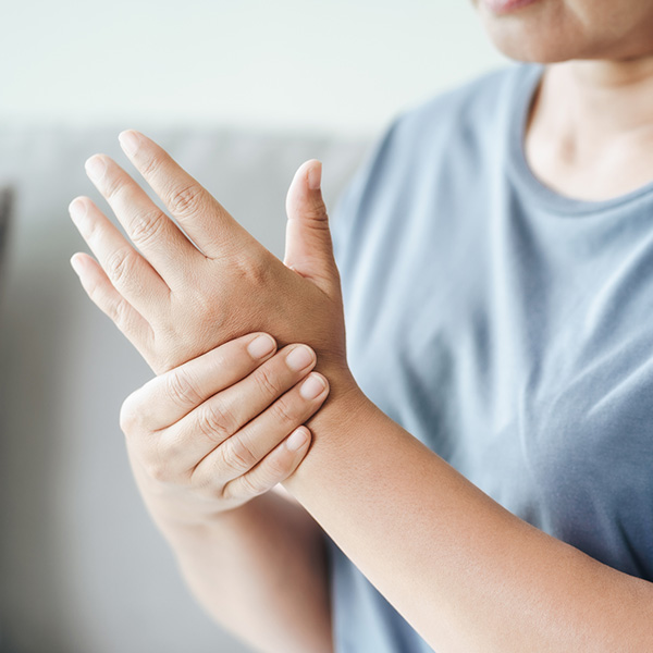 woman sitting on sofa holds her wrist